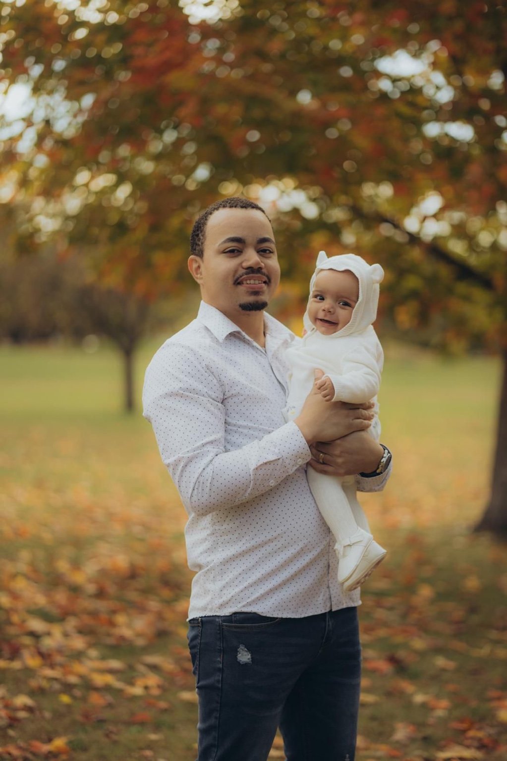 Marlon Araujo, founder of Fifth Gear Watches, holding a baby outdoors.